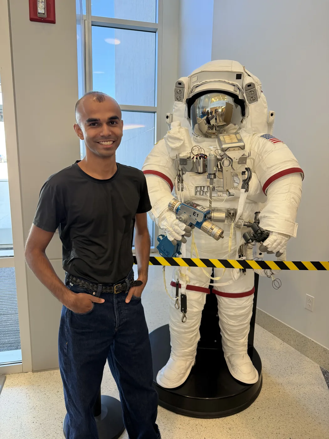 Aamir standing beside a full spacesuit on display at NASA Glenn Research Center
