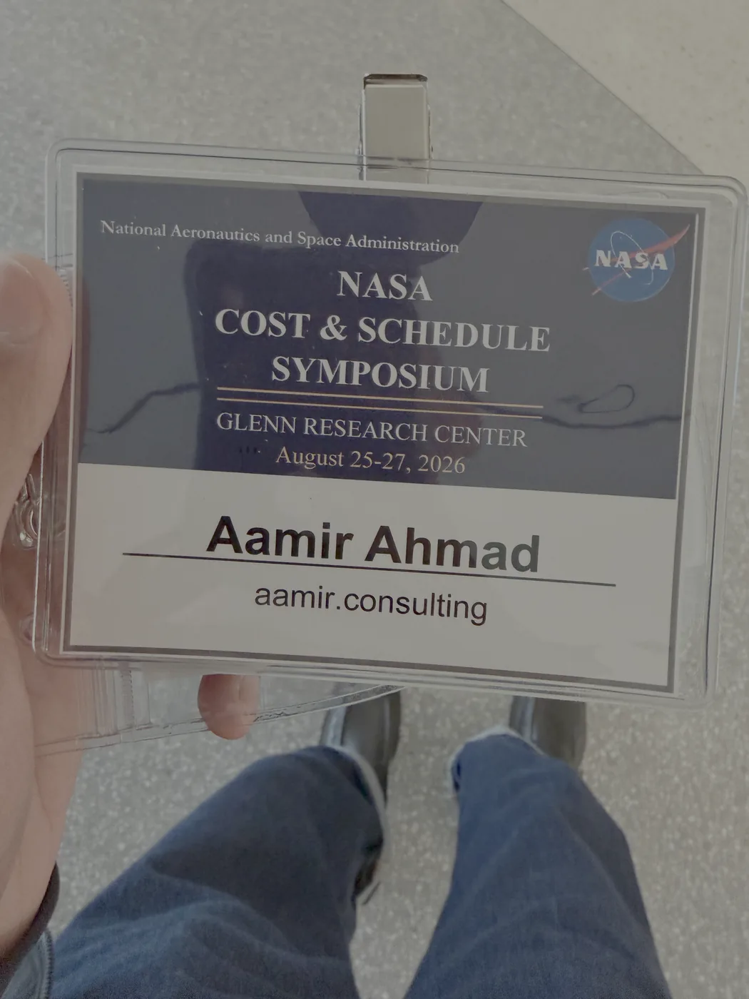 Conference name tag reading NASA Cost and Schedule Symposium, Glenn Research Center, August 25 to 27 2026, Aamir Ahmad, aamir.consulting